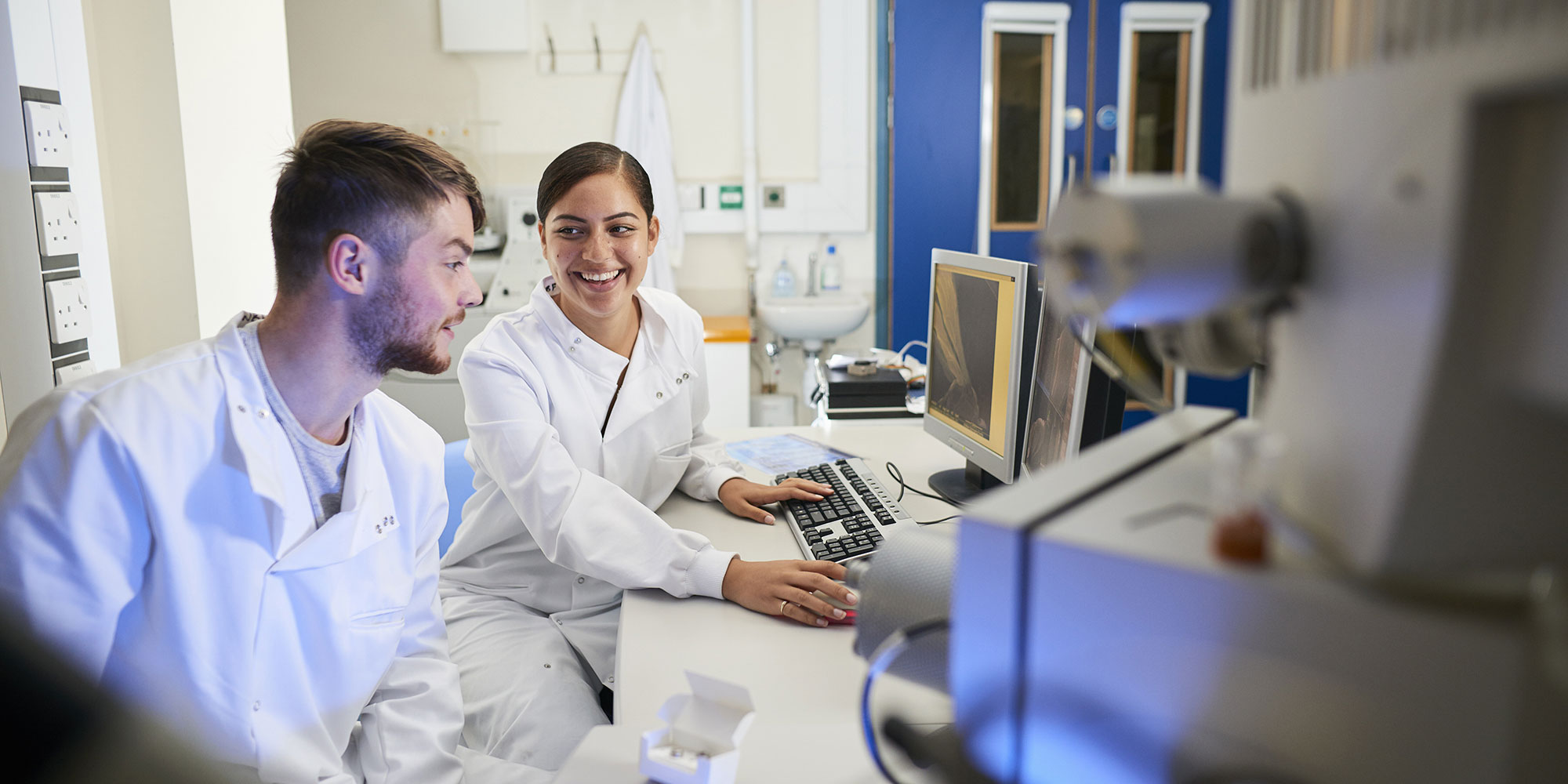 Two researchers talking next to a computer
