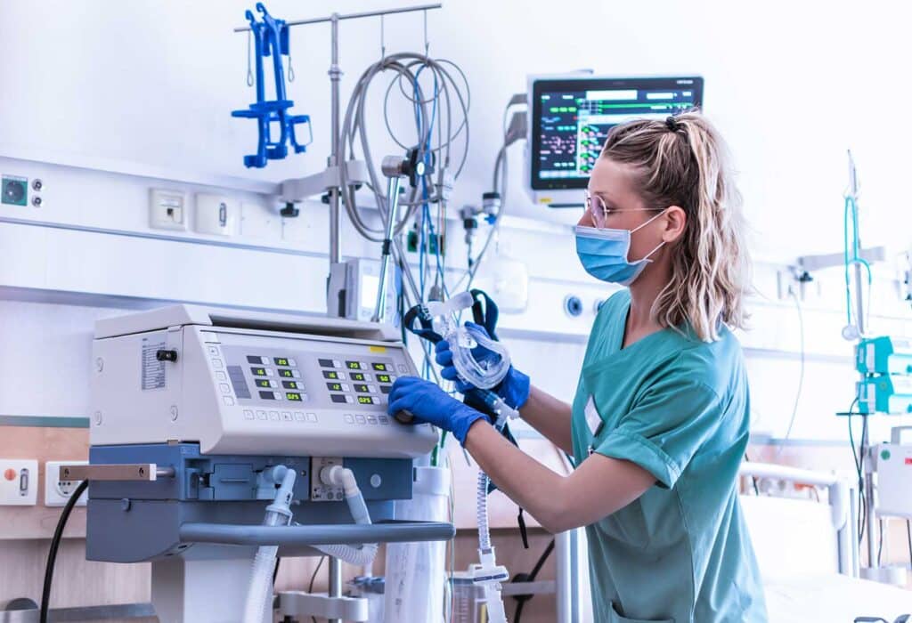 A nurse in a hospital ward adjusting a machine